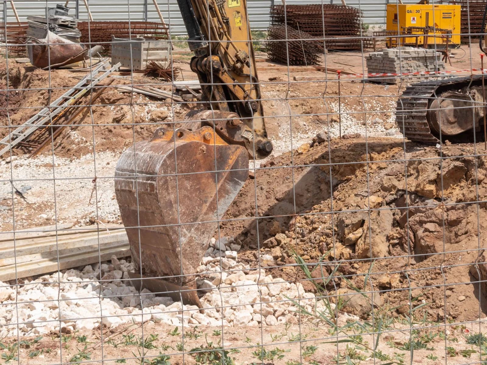 Excavator working open ground, levelling a site before a build begins.